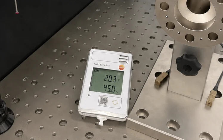 Temperature logger in the measuring room showing 20.3 °C next to a part on the coordinate measuring machine